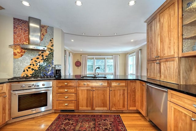 kitchen with appliances with stainless steel finishes, sink, light hardwood / wood-style floors, kitchen peninsula, and wall chimney exhaust hood