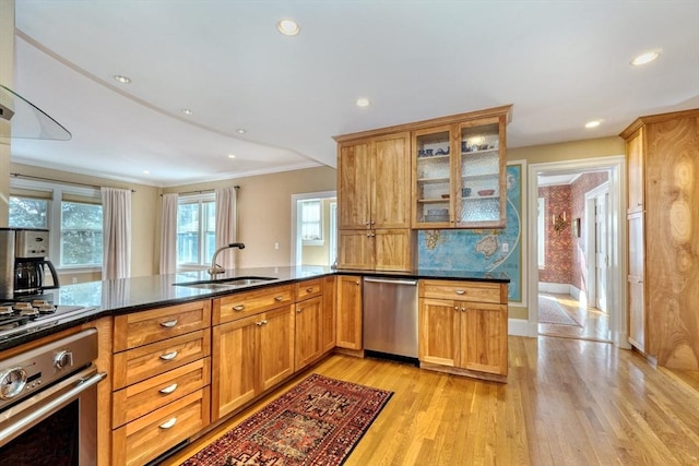 kitchen featuring appliances with stainless steel finishes, sink, ornamental molding, kitchen peninsula, and light hardwood / wood-style flooring