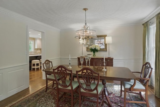 11 Edge Hill Rd, Hopkinton, MA 01748 - dining area with a decorative wall, wood finished floors, a chandelier, wainscoting, and crown molding