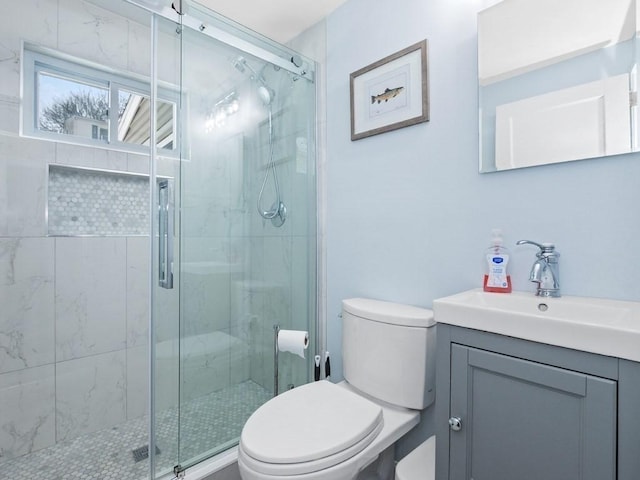 bathroom with a shower with door, vanity, and toilet