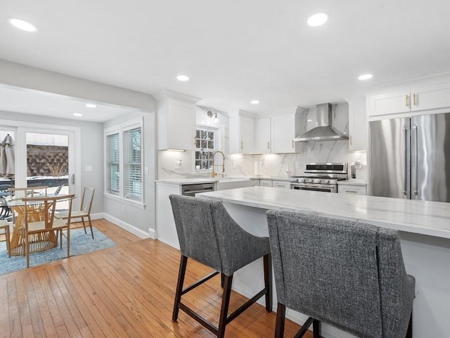 kitchen featuring sink, tasteful backsplash, appliances with stainless steel finishes, wall chimney range hood, and white cabinets