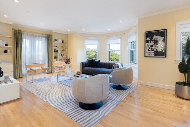 living room with a wealth of natural light, ornamental molding, and light hardwood / wood-style floors