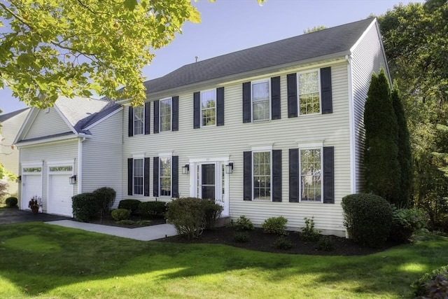 colonial house with a front yard, an attached garage, and aphalt driveway