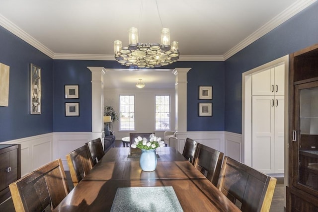 dining room with a wainscoted wall, ornamental molding, and decorative columns