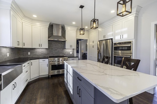 kitchen featuring dark wood-type flooring, a large island, white cabinets, stainless steel appliances, and wall chimney exhaust hood