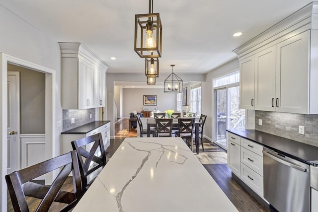 kitchen with dark wood-type flooring, decorative light fixtures, tasteful backsplash, white cabinetry, and dishwasher