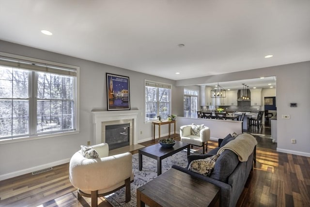 living area featuring visible vents, dark wood-type flooring, baseboards, a fireplace with flush hearth, and recessed lighting