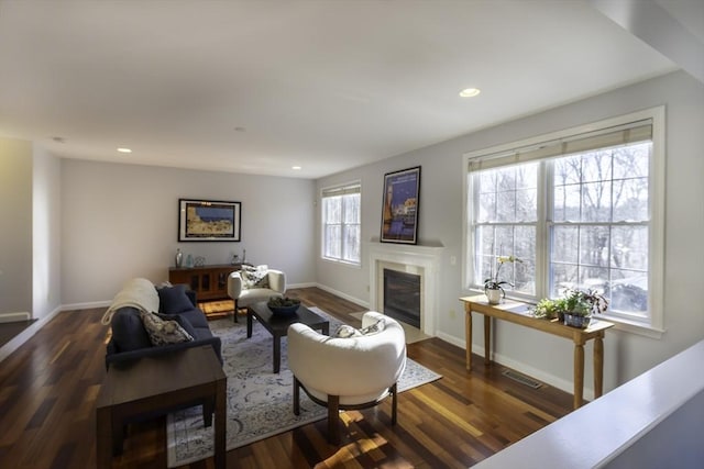 living room with visible vents, recessed lighting, a fireplace with flush hearth, and wood finished floors