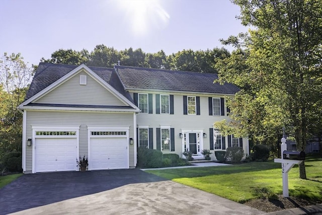 colonial-style house featuring a front lawn, a garage, and driveway