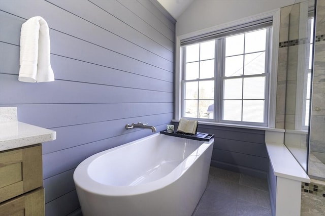 full bath with tile patterned floors, a freestanding bath, vanity, and lofted ceiling