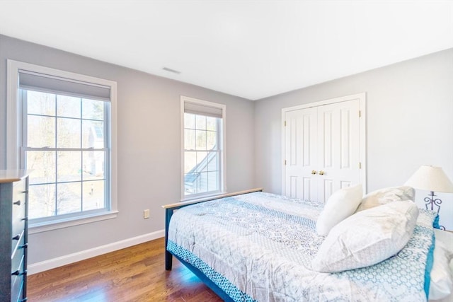 bedroom with multiple windows, wood finished floors, and baseboards