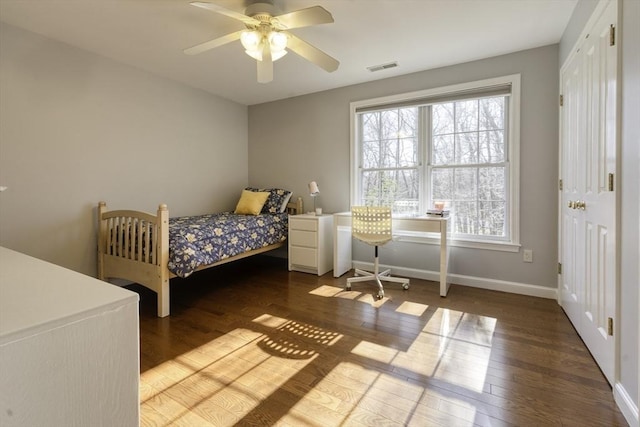 bedroom featuring a ceiling fan, wood finished floors, visible vents, and baseboards