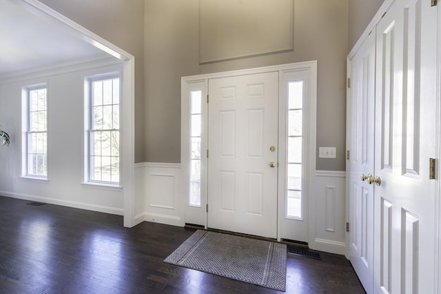 foyer entrance featuring a wainscoted wall, dark wood finished floors, and a decorative wall