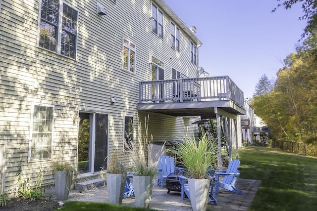 back of house with a patio, a fire pit, a deck, and a lawn