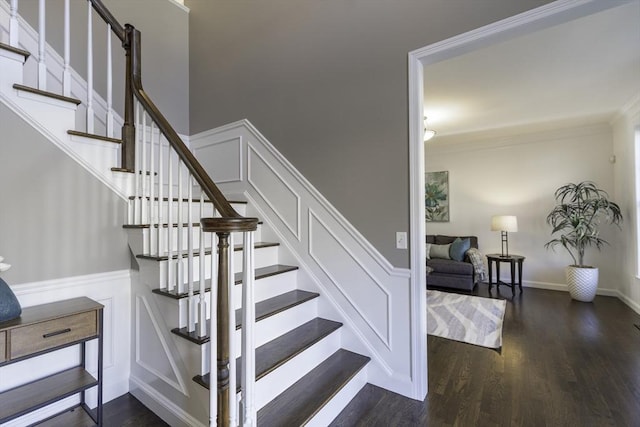 stairway with a decorative wall, a wainscoted wall, wood finished floors, and ornamental molding