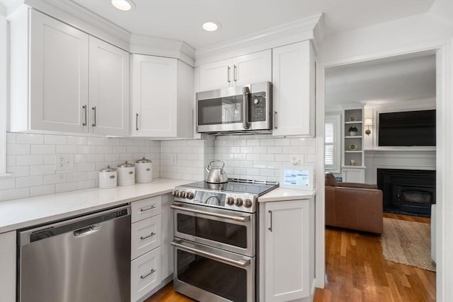 kitchen with light wood-type flooring, light countertops, white cabinetry, and appliances with stainless steel finishes