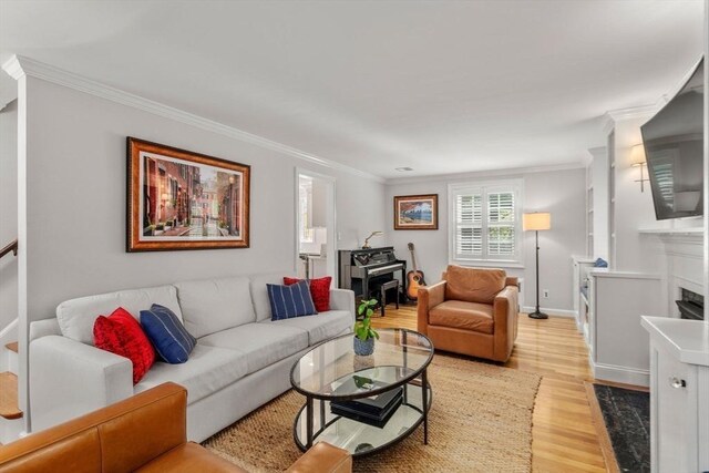 living area with light wood finished floors, baseboards, crown molding, a fireplace, and a wood stove