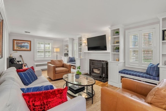 living area featuring radiator heating unit, light wood-style floors, a wood stove, and crown molding