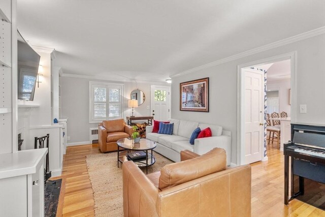 living area with baseboards, ornamental molding, and light wood finished floors
