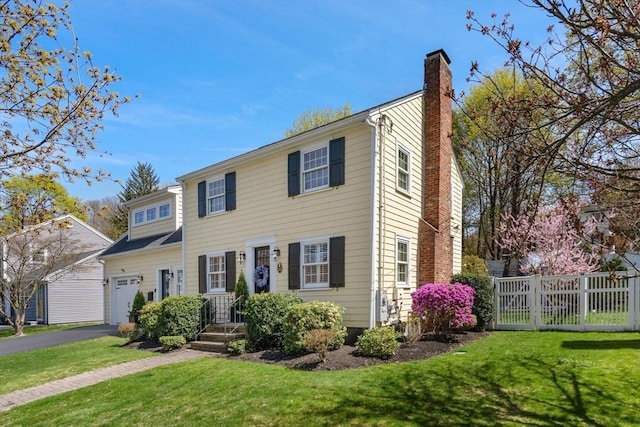 colonial house with a chimney, a front lawn, fence, and a garage