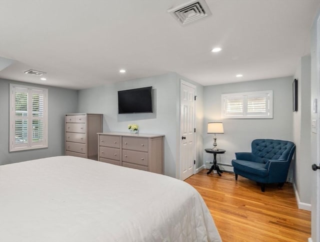 bedroom featuring baseboards, light wood-style flooring, visible vents, and baseboard heating