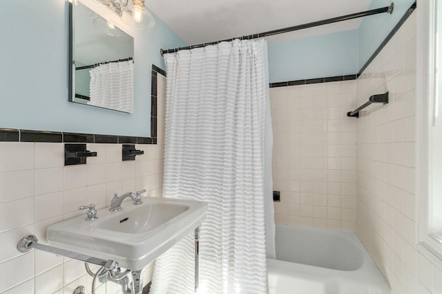 bathroom featuring tile walls, a sink, and shower / bath combination with curtain