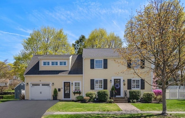 view of front of property featuring driveway, a shingled roof, a front lawn, and fence