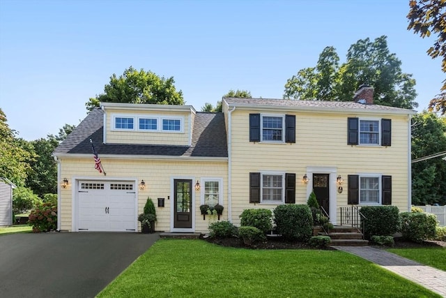 view of front of home with a front lawn, a chimney, aphalt driveway, and a garage