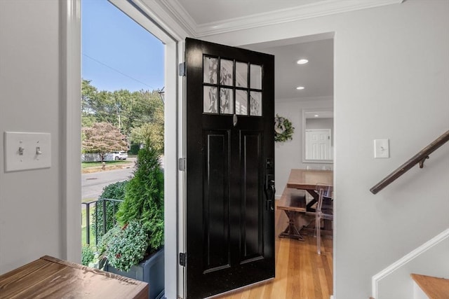 entryway with stairway, ornamental molding, wood finished floors, and a healthy amount of sunlight