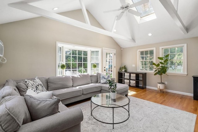 living area with wood finished floors, a ceiling fan, beamed ceiling, a skylight, and baseboards
