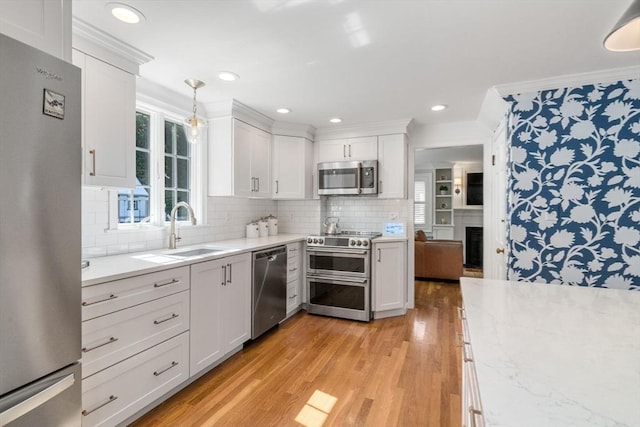 kitchen with plenty of natural light, light wood finished floors, stainless steel appliances, a sink, and white cabinetry