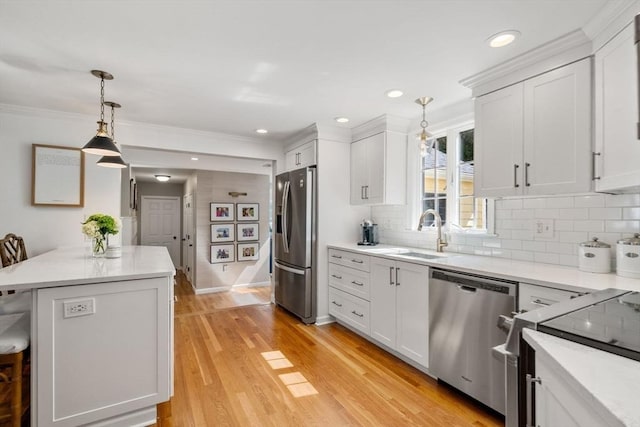 kitchen with stainless steel appliances, a sink, white cabinetry, and hanging light fixtures