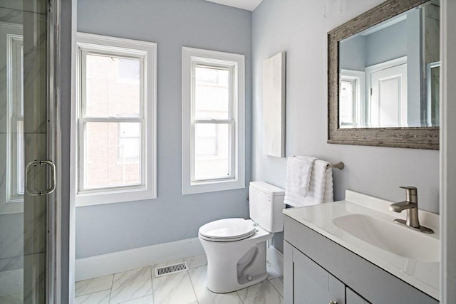 bathroom featuring a healthy amount of sunlight, toilet, a shower with shower door, and vanity