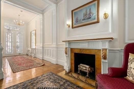 sitting room featuring a notable chandelier, french doors, a fireplace with flush hearth, and a decorative wall