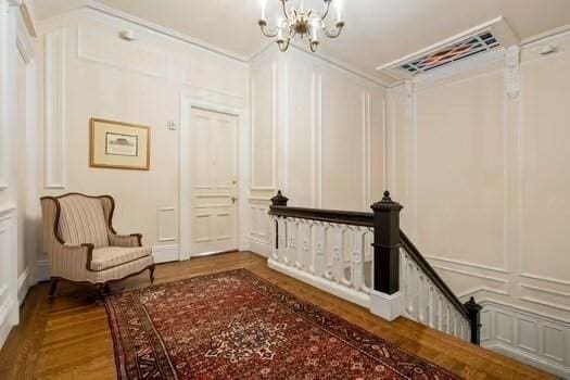 corridor with a chandelier, wood finished floors, and a decorative wall