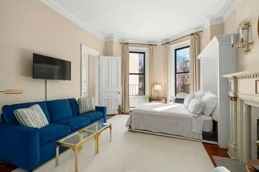 bedroom featuring a fireplace with flush hearth and crown molding