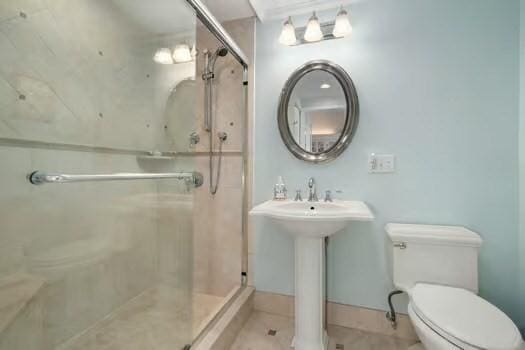 bathroom featuring a stall shower, toilet, and tile patterned floors