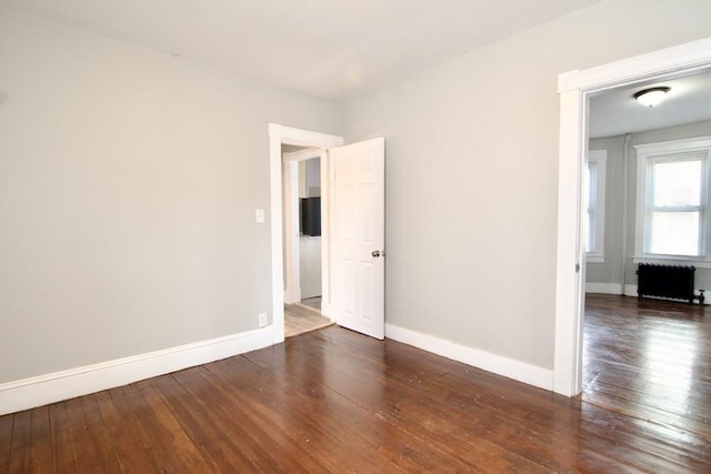 empty room featuring radiator and dark hardwood / wood-style flooring