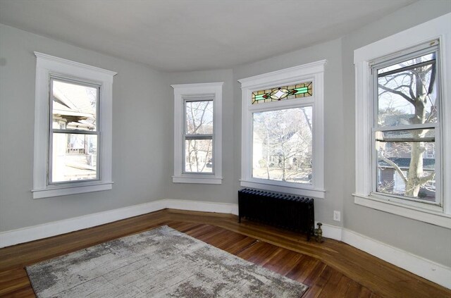 unfurnished room with dark hardwood / wood-style floors and radiator