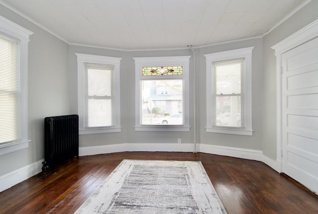 empty room featuring crown molding, radiator, a wealth of natural light, and dark hardwood / wood-style flooring