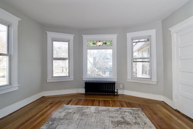 spare room featuring wood-type flooring and radiator