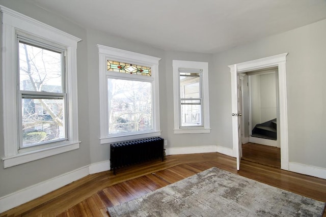 interior space with radiator heating unit, dark hardwood / wood-style flooring, and multiple windows