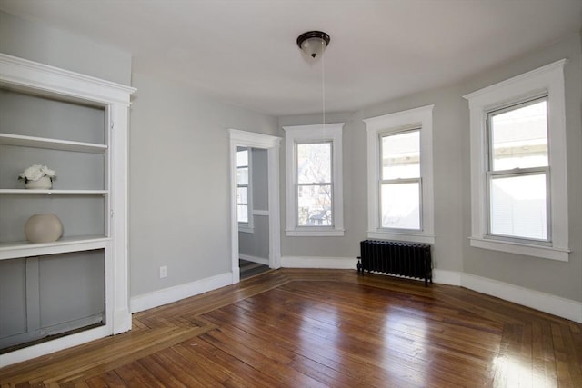 unfurnished dining area with radiator heating unit and dark hardwood / wood-style flooring