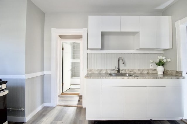 kitchen featuring sink, white cabinets, and light wood-type flooring