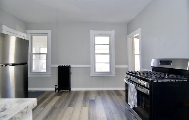 kitchen featuring hardwood / wood-style flooring, radiator, and appliances with stainless steel finishes