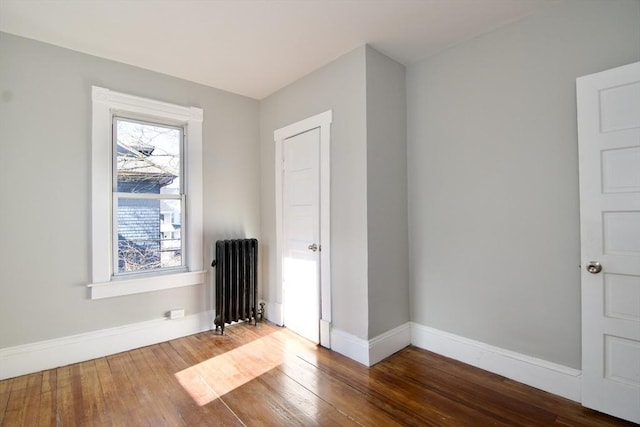 unfurnished room featuring wood-type flooring, radiator, and a healthy amount of sunlight