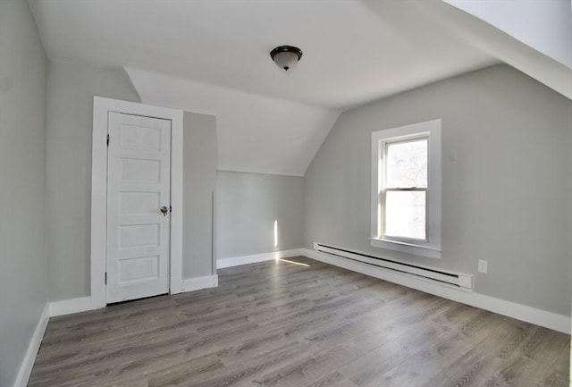 additional living space featuring vaulted ceiling, a baseboard heating unit, and light hardwood / wood-style floors