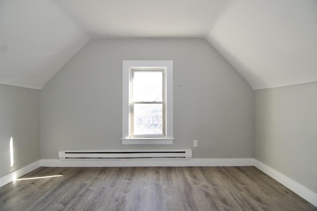 additional living space with baseboard heating, hardwood / wood-style flooring, and vaulted ceiling