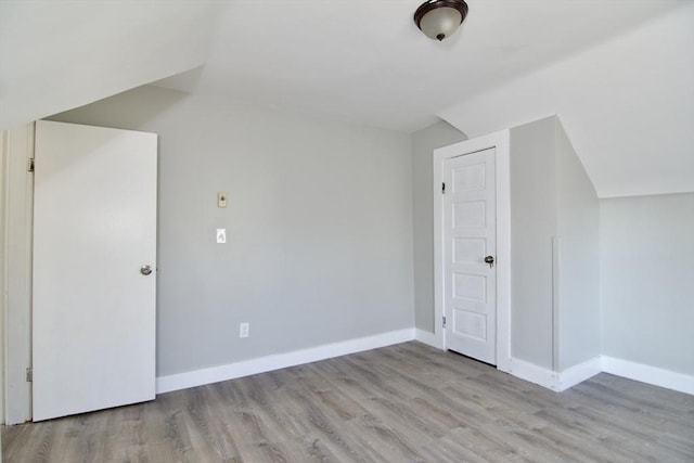 additional living space featuring light hardwood / wood-style flooring and vaulted ceiling