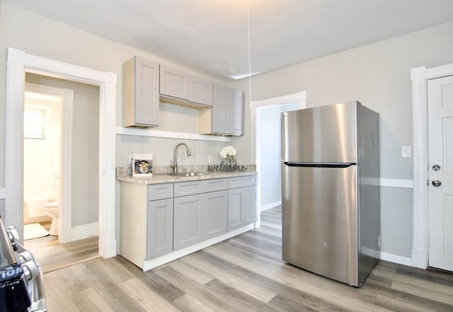 kitchen with sink, light hardwood / wood-style floors, gray cabinets, and stainless steel fridge